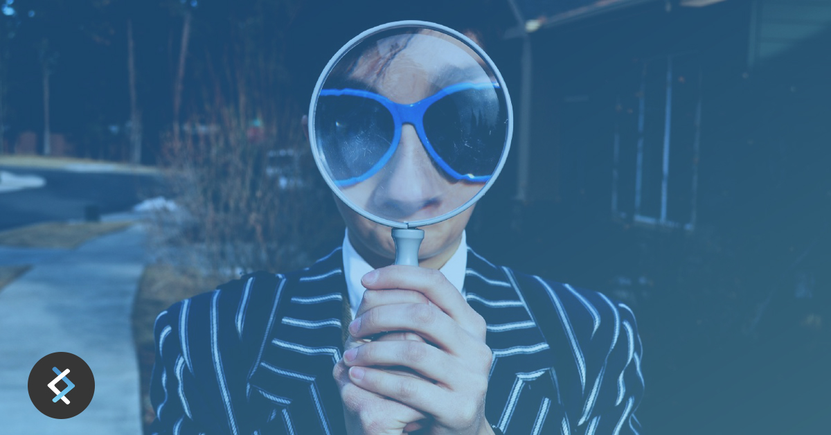 Man in sunglasses and suit looking throughout magnifying glass